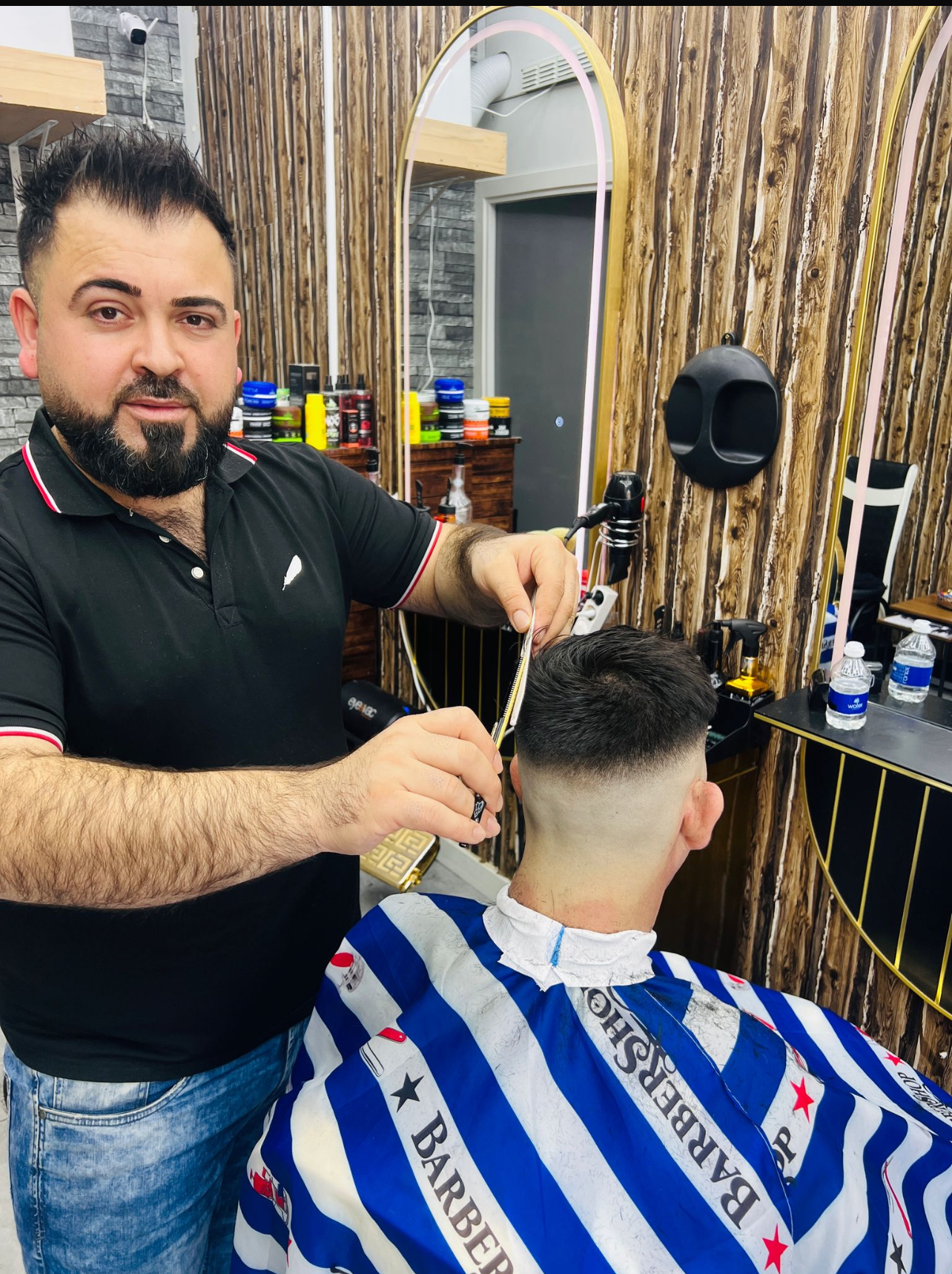 De barbier aan het werk bij de gouden spiegels en houten lattenwand